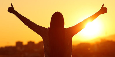 female outline in the sun with both thumbs up