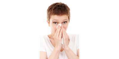 woman sneezing into tissue