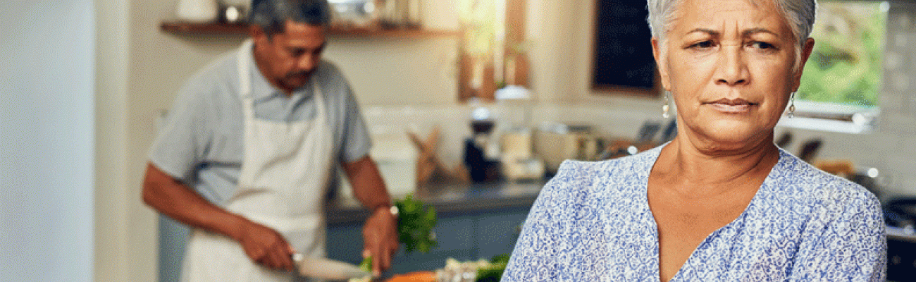 Wife clearly angry while husband is cooking in the background
