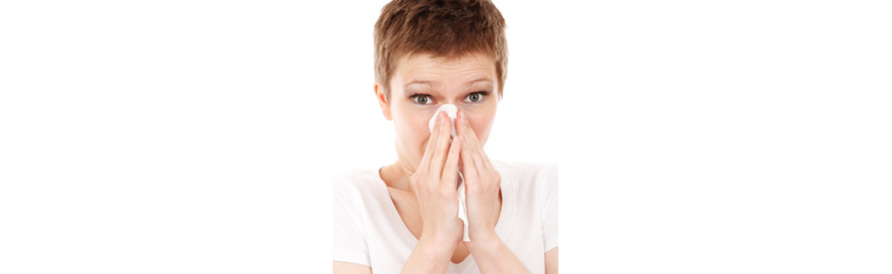 woman sneezing into tissue